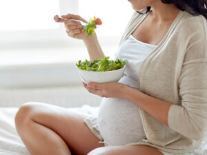 close up of pregnant woman eating salad at home